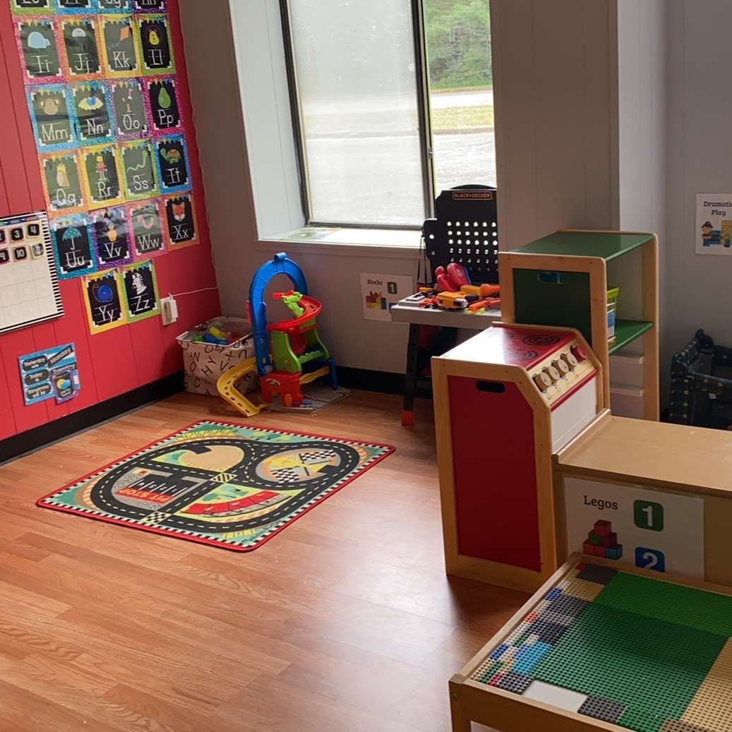 A room with a lot of toys on the floor and a rug on the floor.