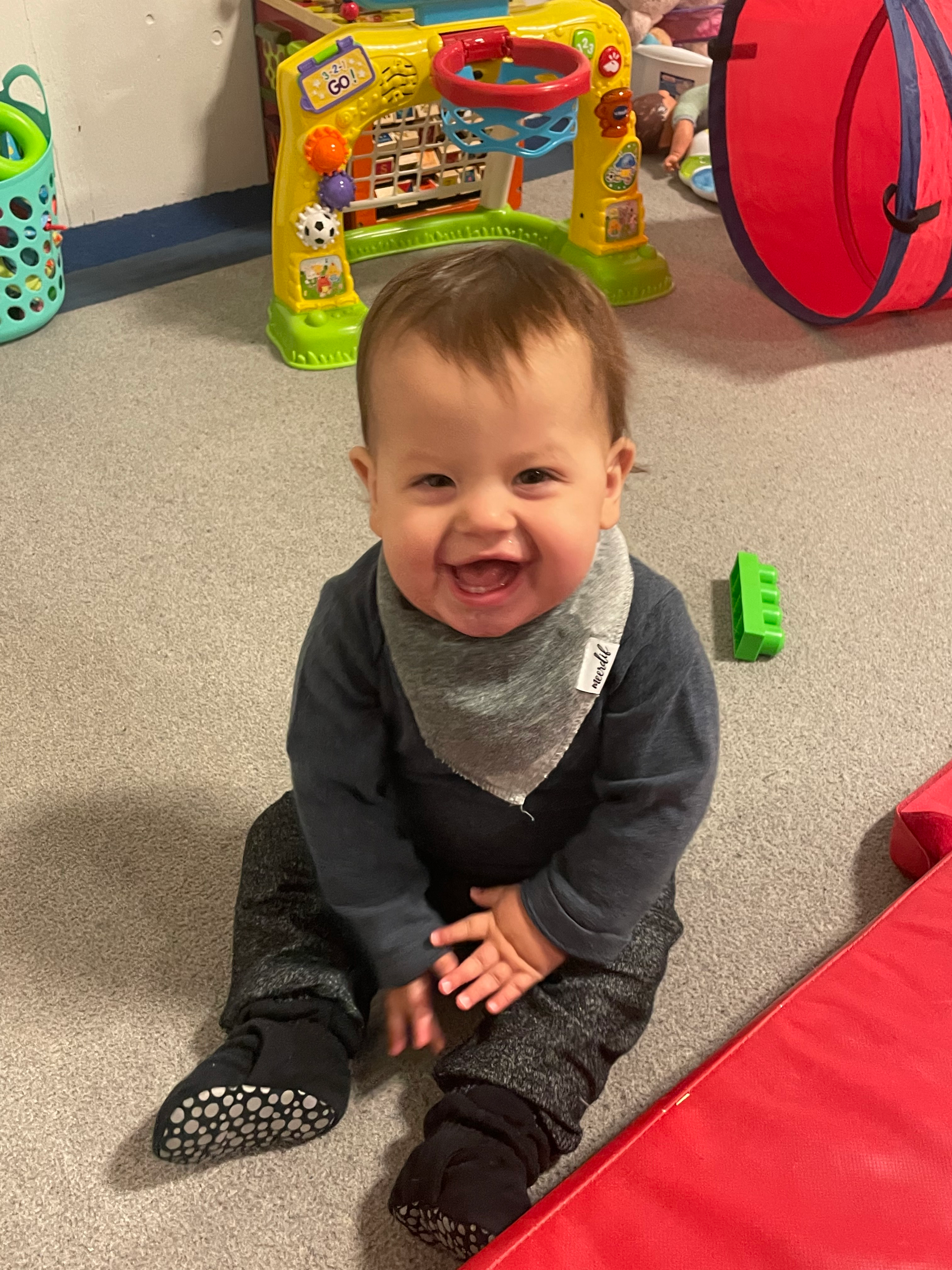 A baby is sitting on the floor in a room with toys.