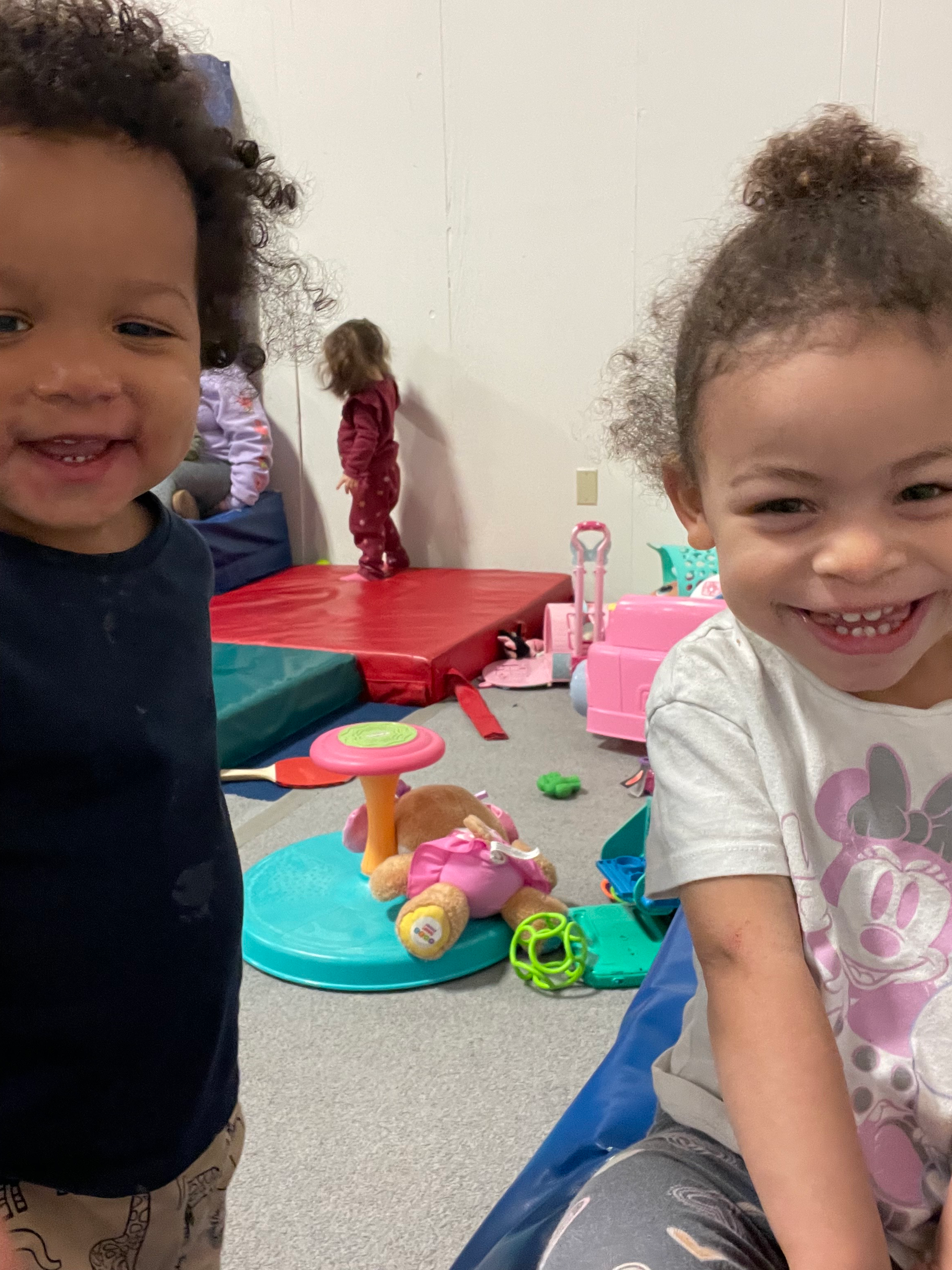 A boy and a girl are standing next to each other in a room filled with toys.