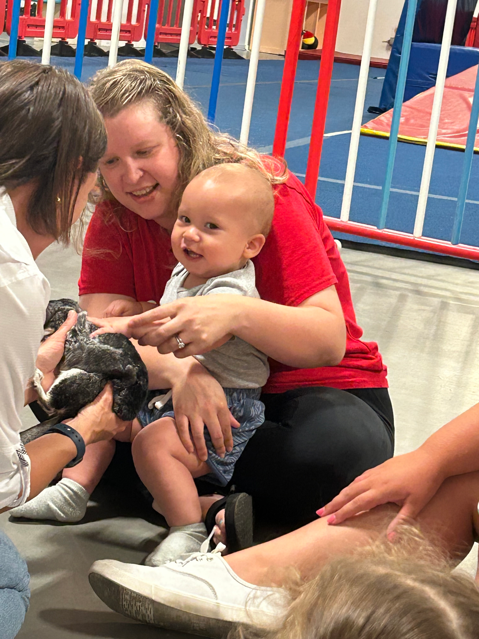 A woman is holding a baby in her arms while sitting on the floor.