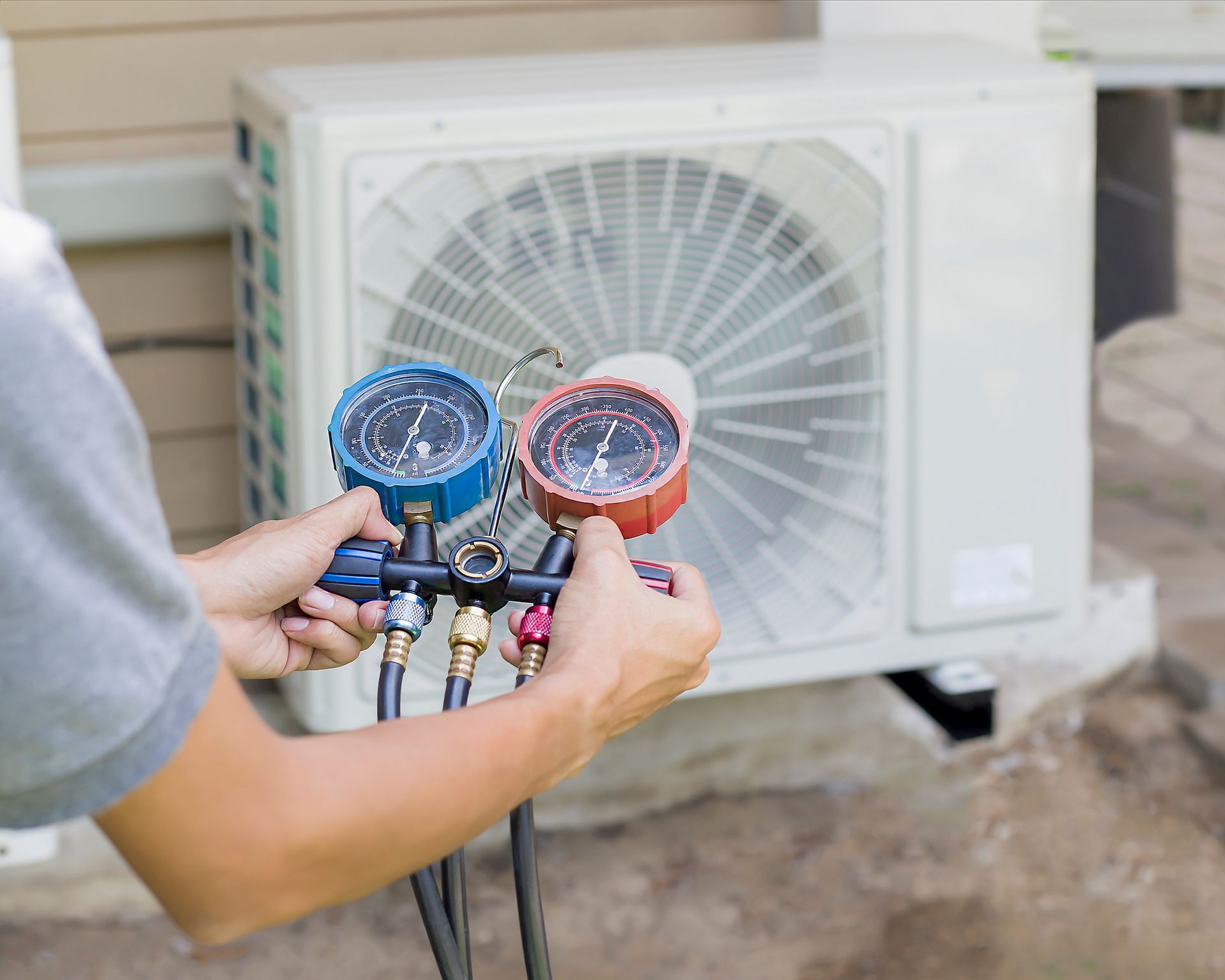 Close-up of a technician performing cooling services, using measuring equipment for the unit.