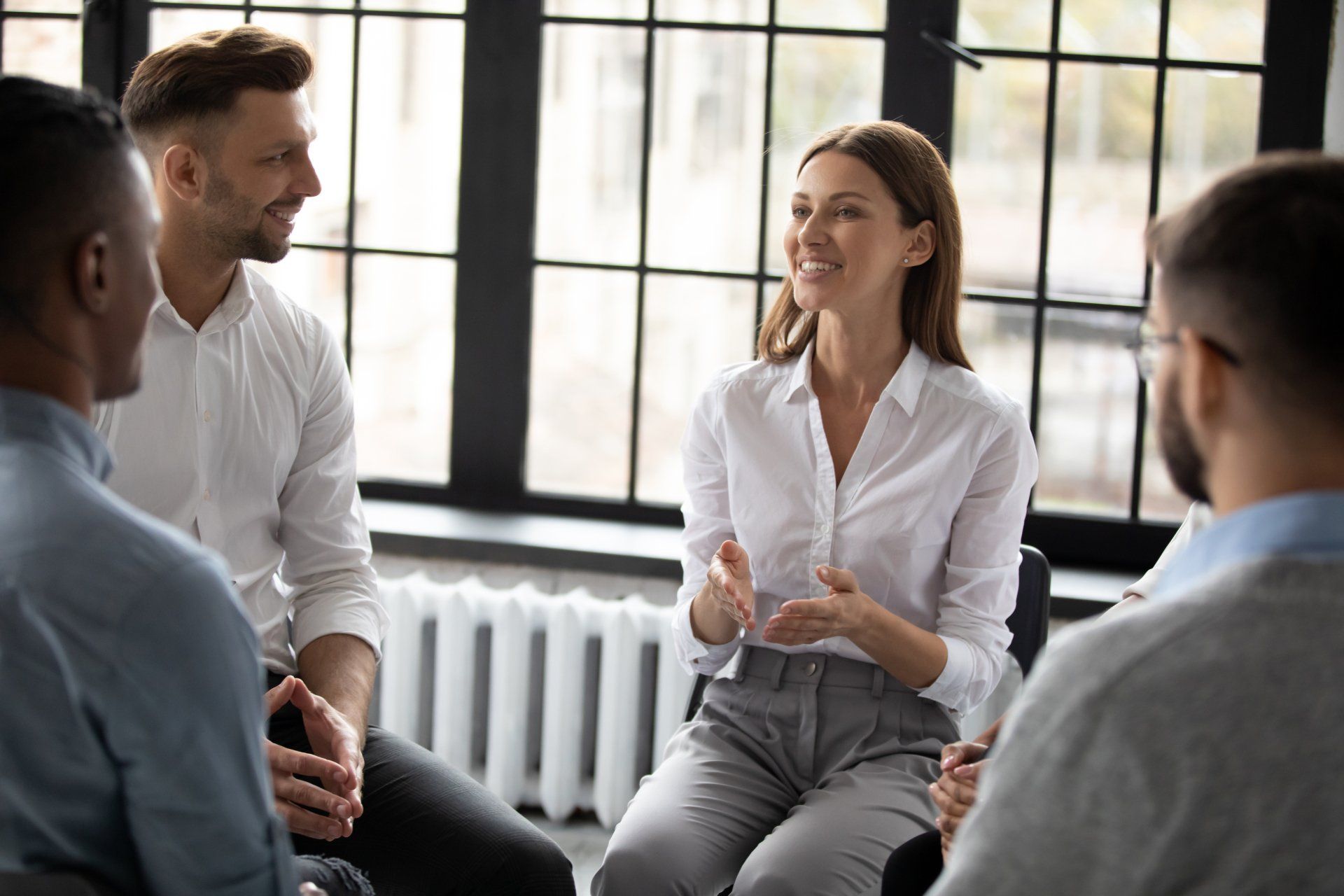 Confident smiling woman coach speaking at meeting, happy diverse people sitting in circle
