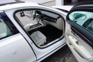 White car with both doors open, showing a beige interior and black trim in a garage.