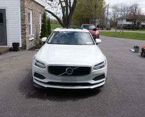 White Volvo SUV parked in a driveway beside a house on a suburban street