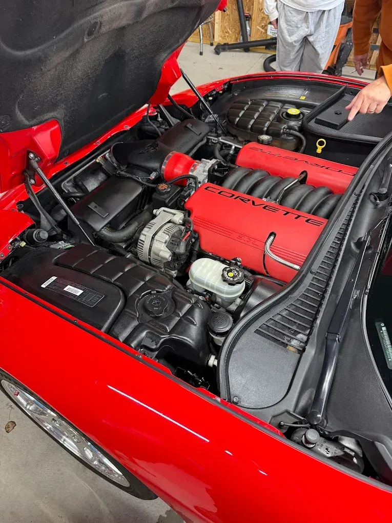 Red sports car engine bay with red engine cover and open rear hatch