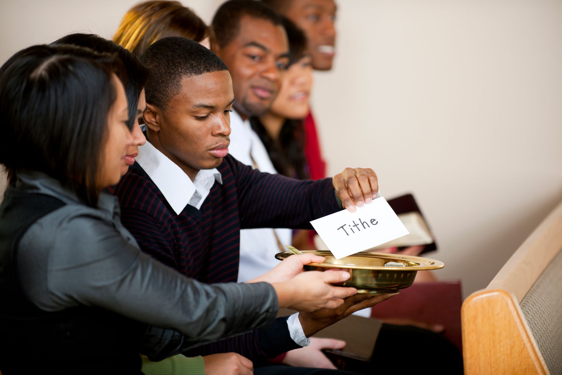 A group of people are sitting in a church and one of them is holding a card that says title