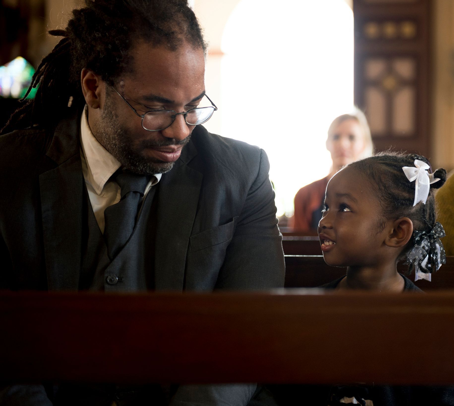 A man in a suit and tie is talking to a little girl