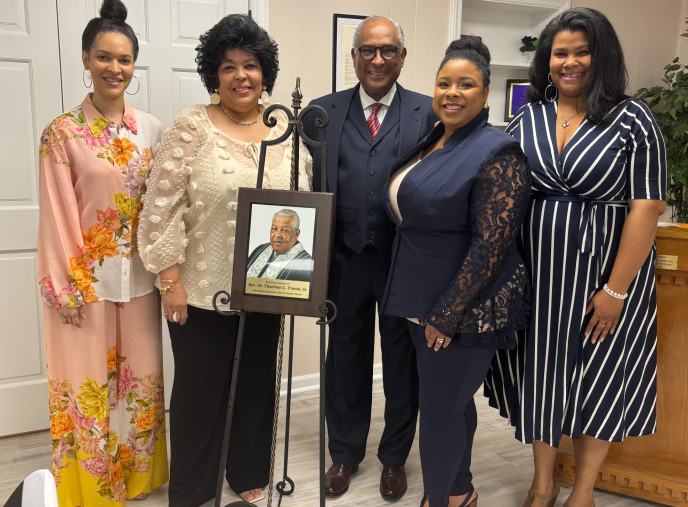 A group of women are standing next to each other holding a picture of a man.