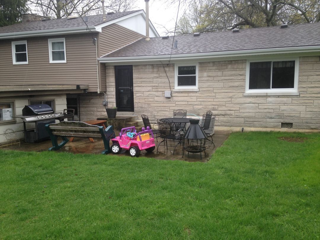 A pink toy car is parked in the backyard of a house.