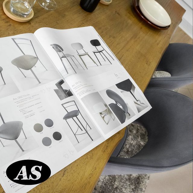 Catalogo di mobili aperto su un tavolo di legno, con sedie e colori esposti.