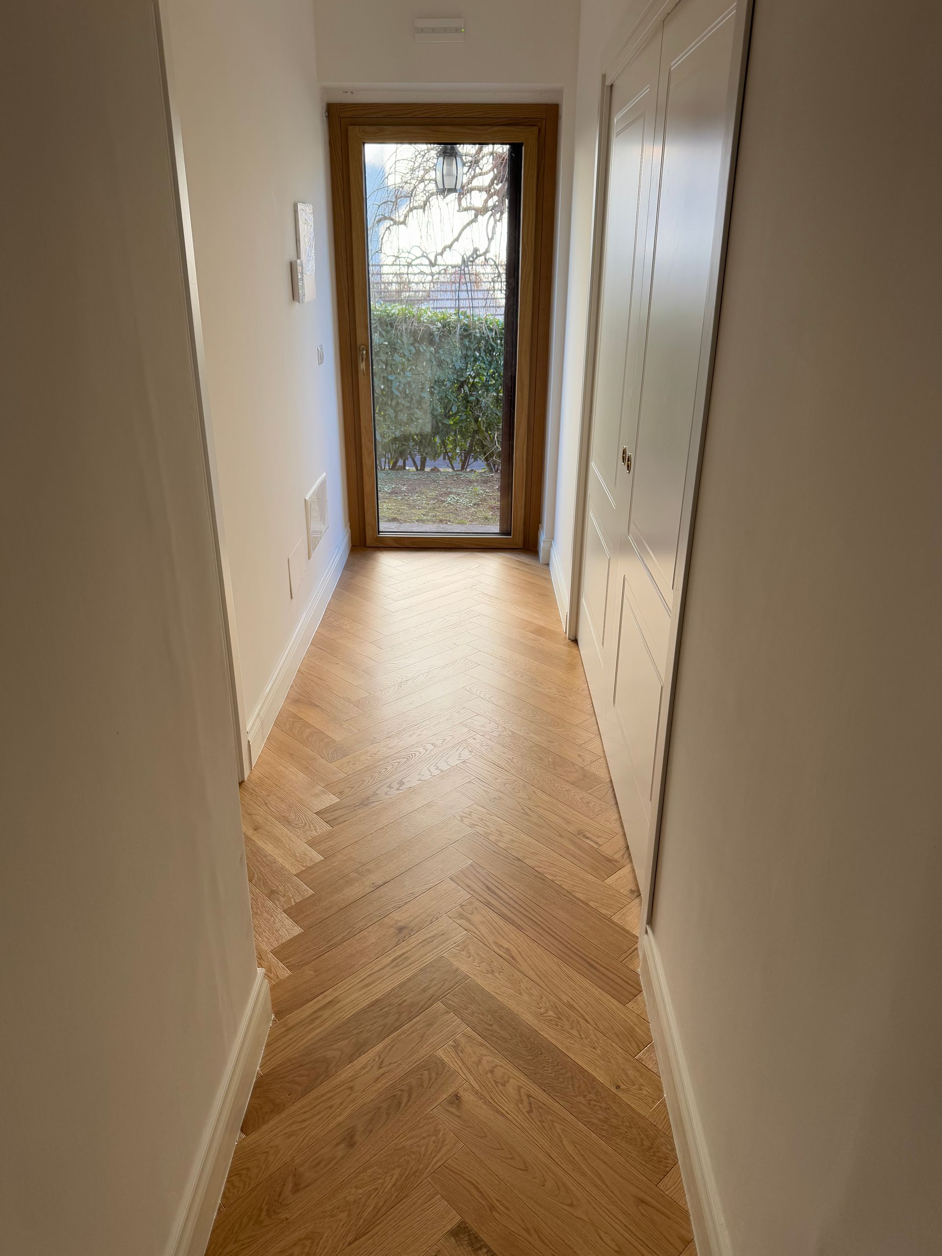 Soggiorno moderno con camino, divani bianchi, pavimento in legno e ampie finestre.