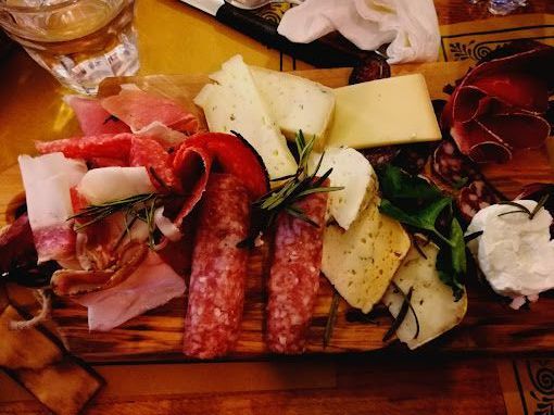 Un tagliere di legno pieno di una varietà di carni e formaggi