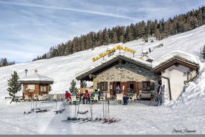 Un gruppo di persone è seduto fuori da un edificio nella neve.