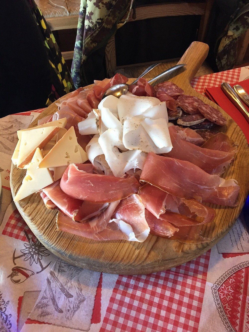 Un tagliere di legno pieno di carne e formaggio su un tavolo.