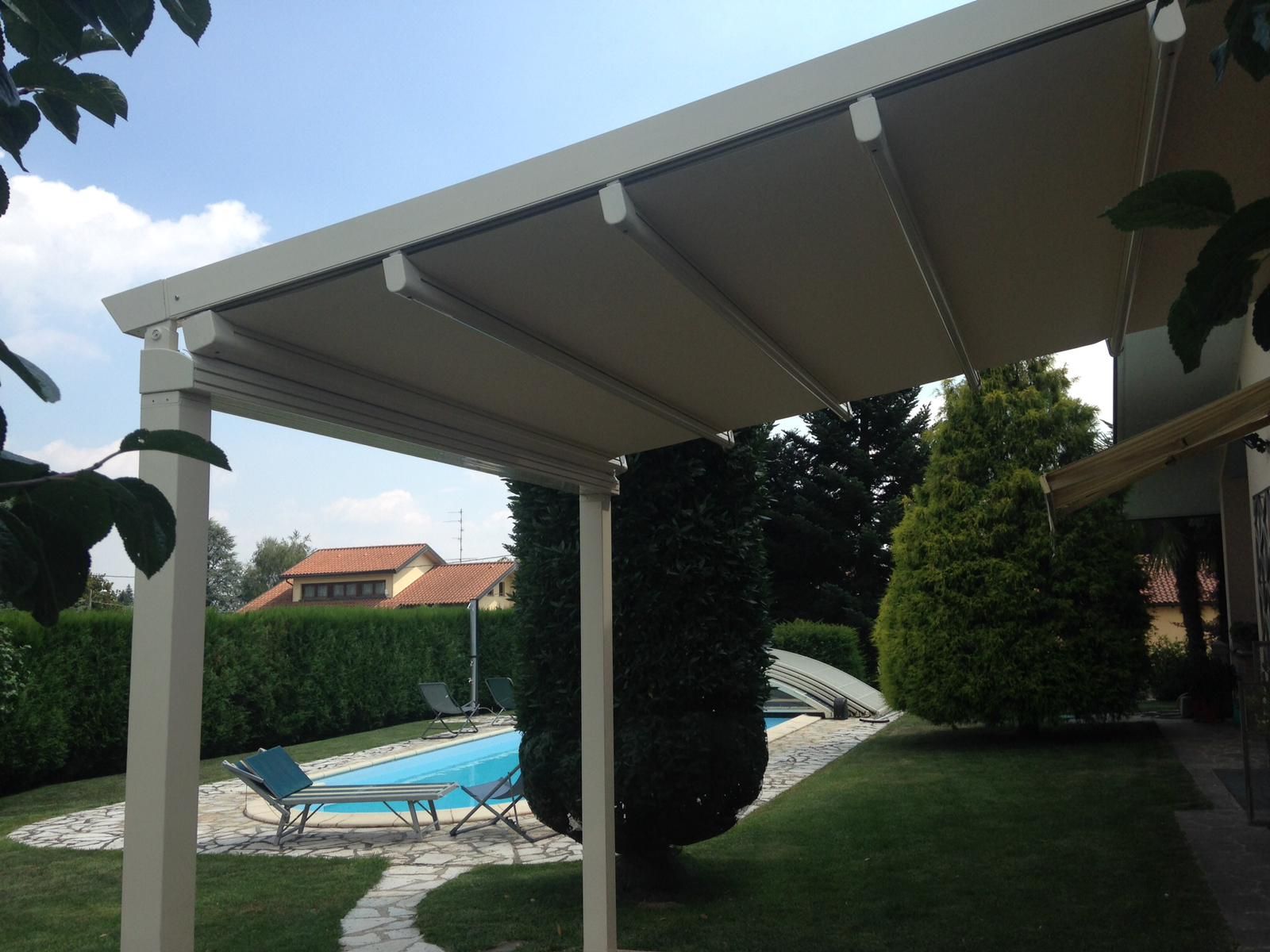 Una tenda da sole retrattile beige si estende su un prato verde accanto alla piscina nel cortile.