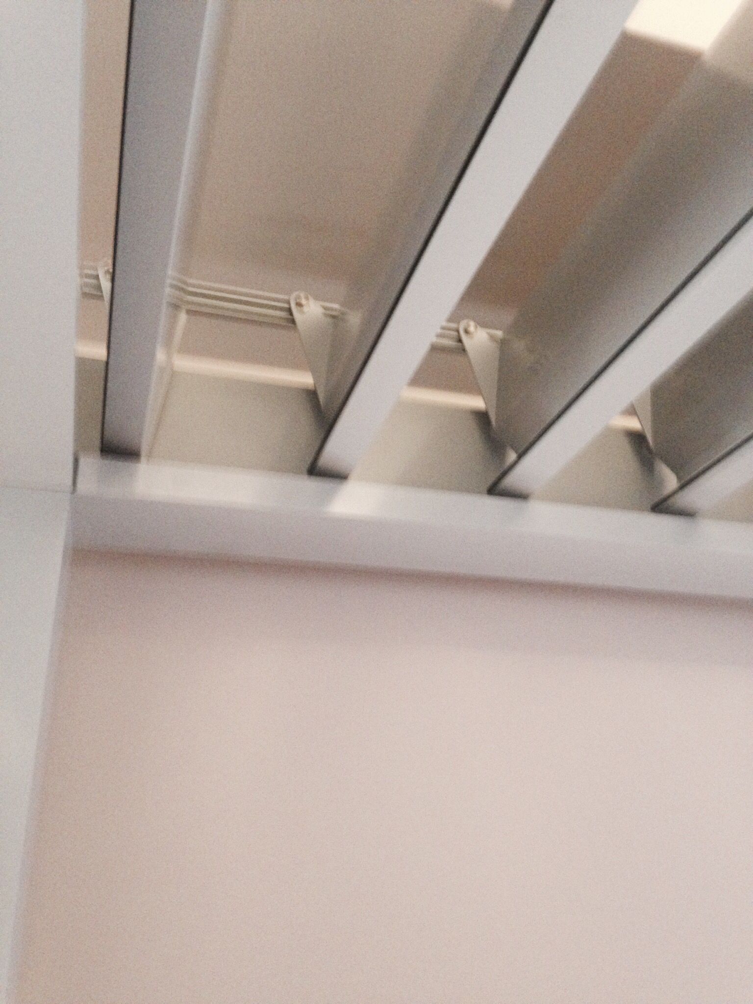 Vista dal basso di travi a vista bianche e modanature interne su uno sfondo beige.