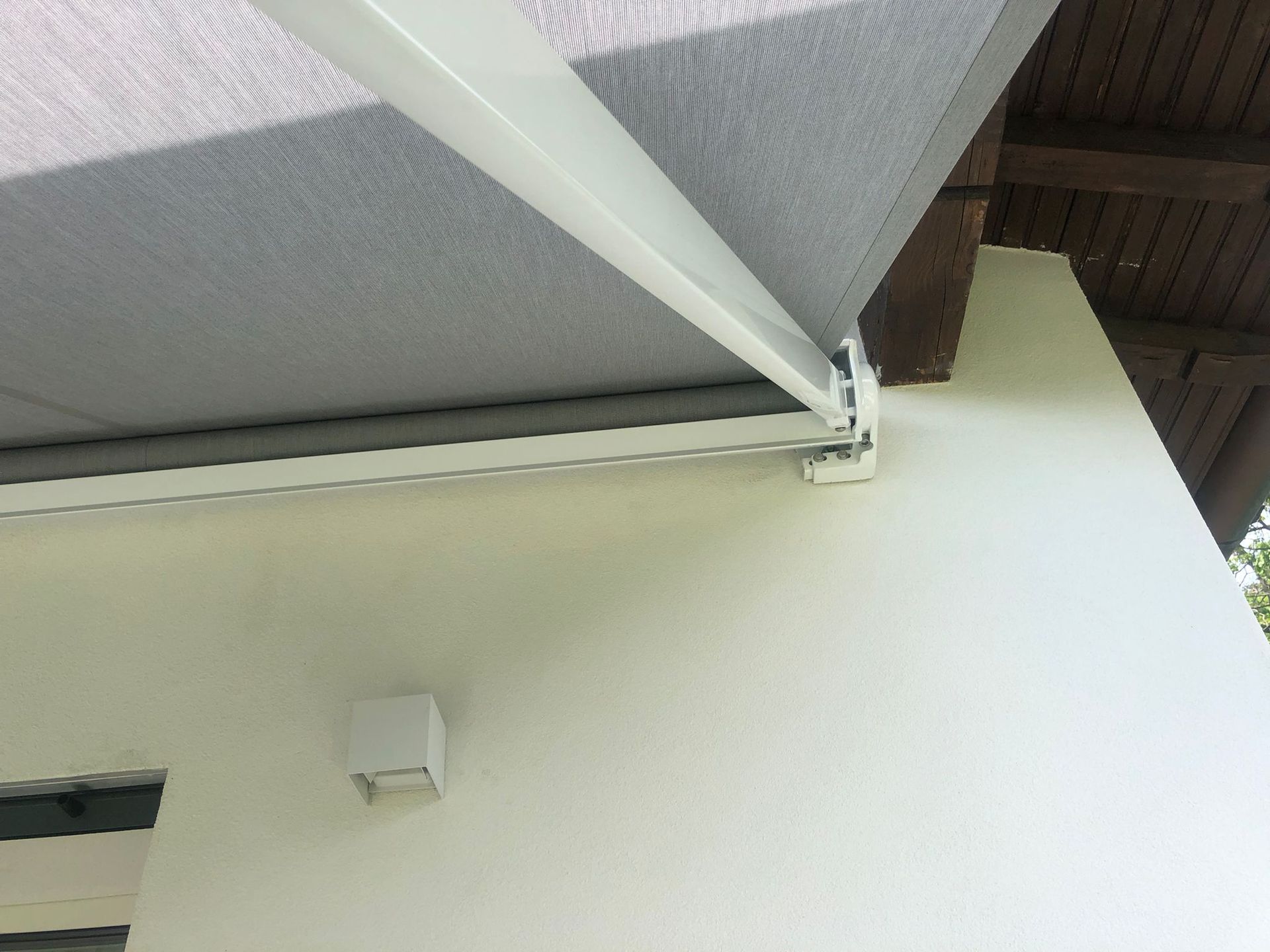 Primo piano di una tenda da sole retrattile bianca montata su una parete semplice e chiara, con tessuto grigio esteso.