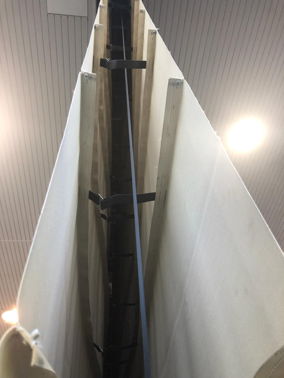 Vista dal basso di due pannelli color bianco sporco tenuti insieme da staffe metalliche scure e da una fascia verticale blu centrale.