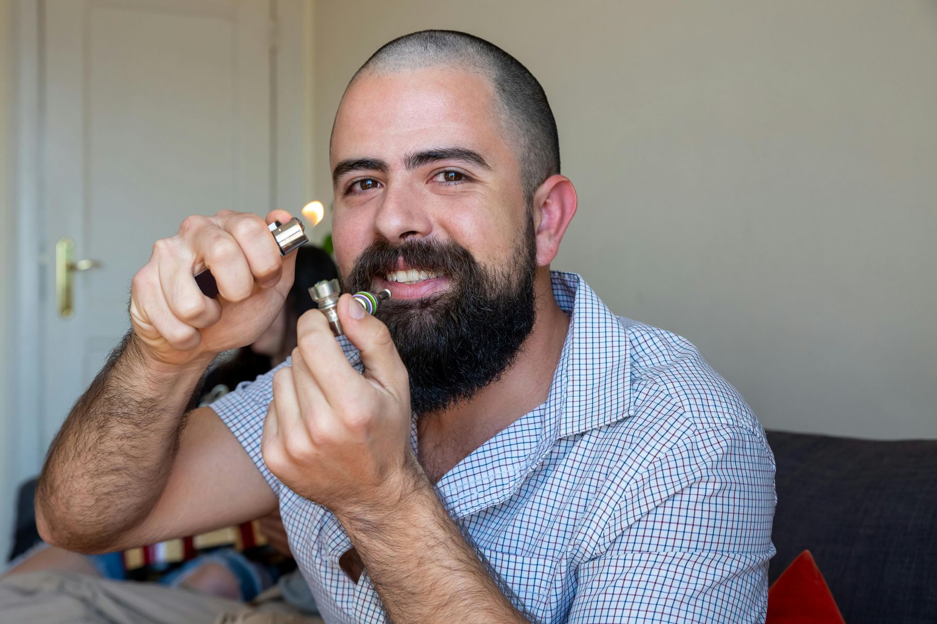 Man smiling while holding a small object near his face in a room