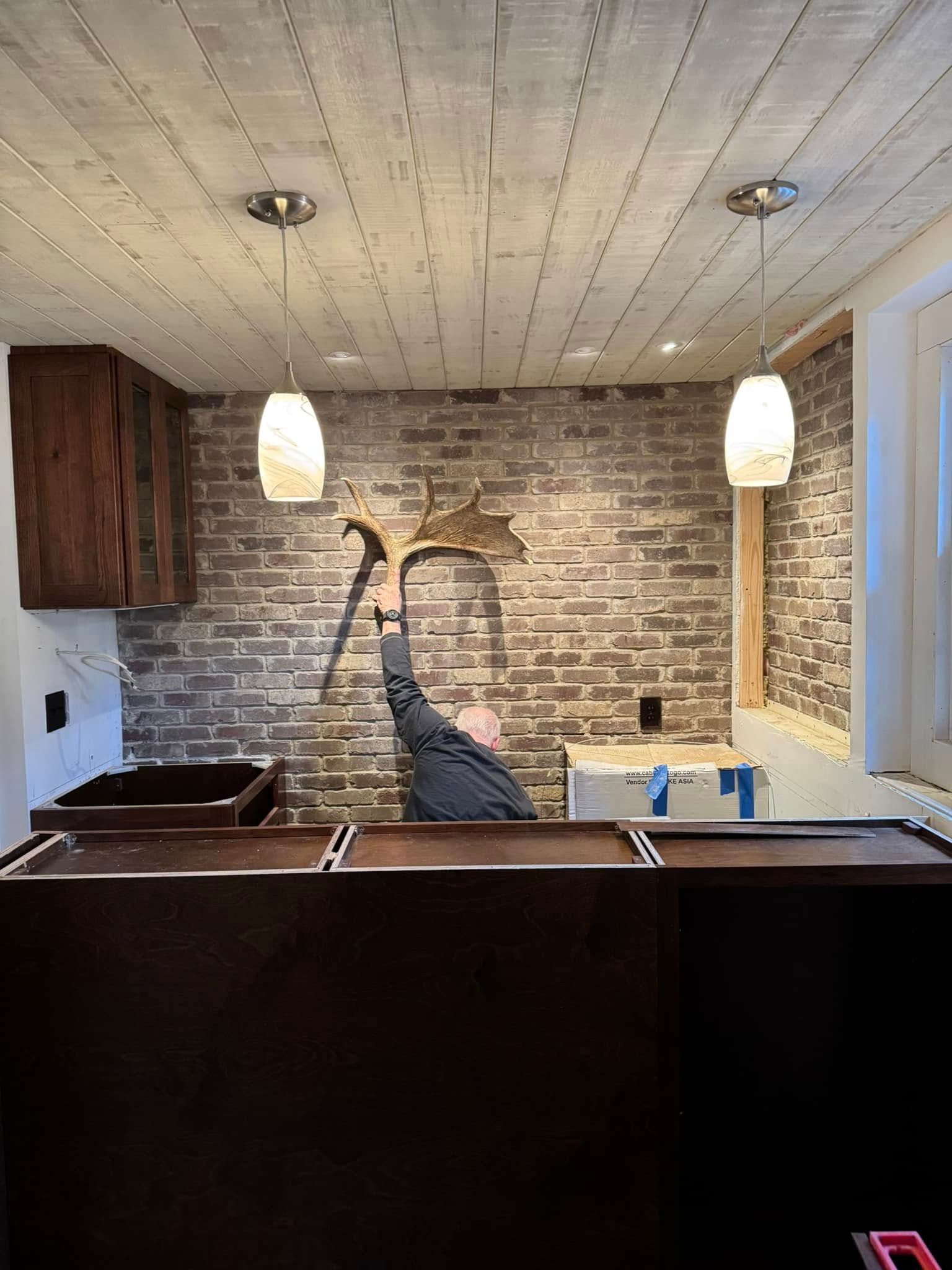 A man is sitting in a room with a brick wall and a pool table.