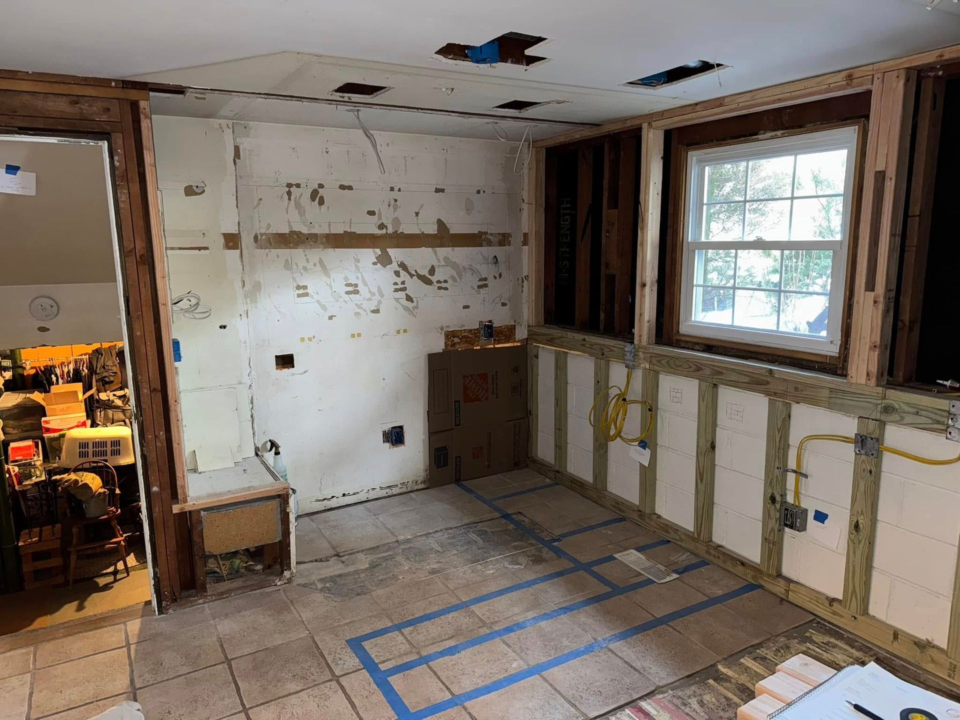 A kitchen that is being remodeled with blue tape on the floor.