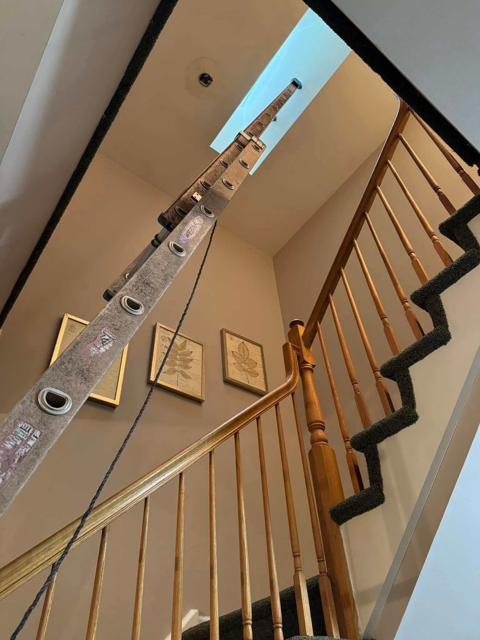 A ladder is hanging from the railing of a staircase.