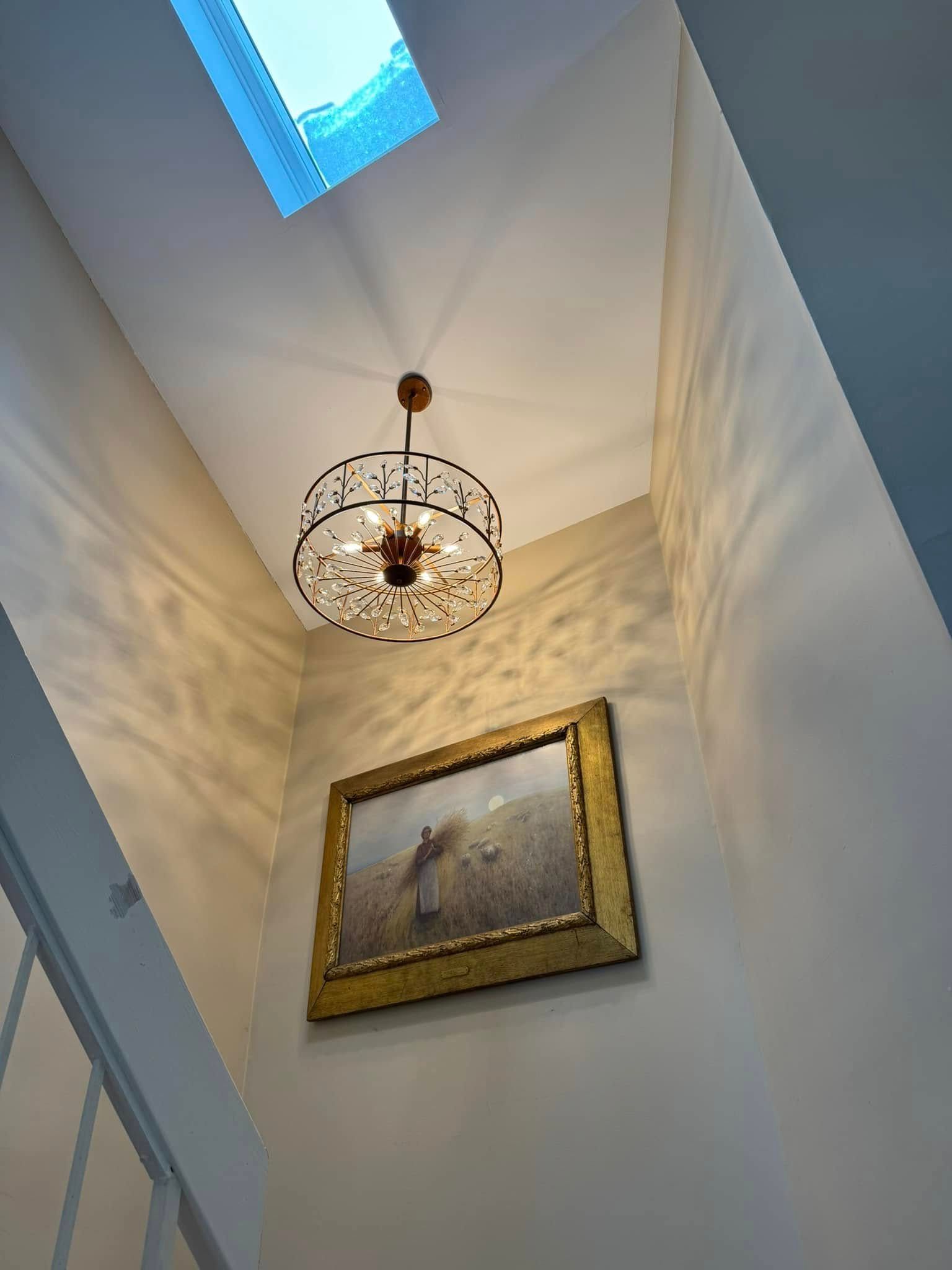 There is a picture on the wall and a chandelier hanging from the ceiling.