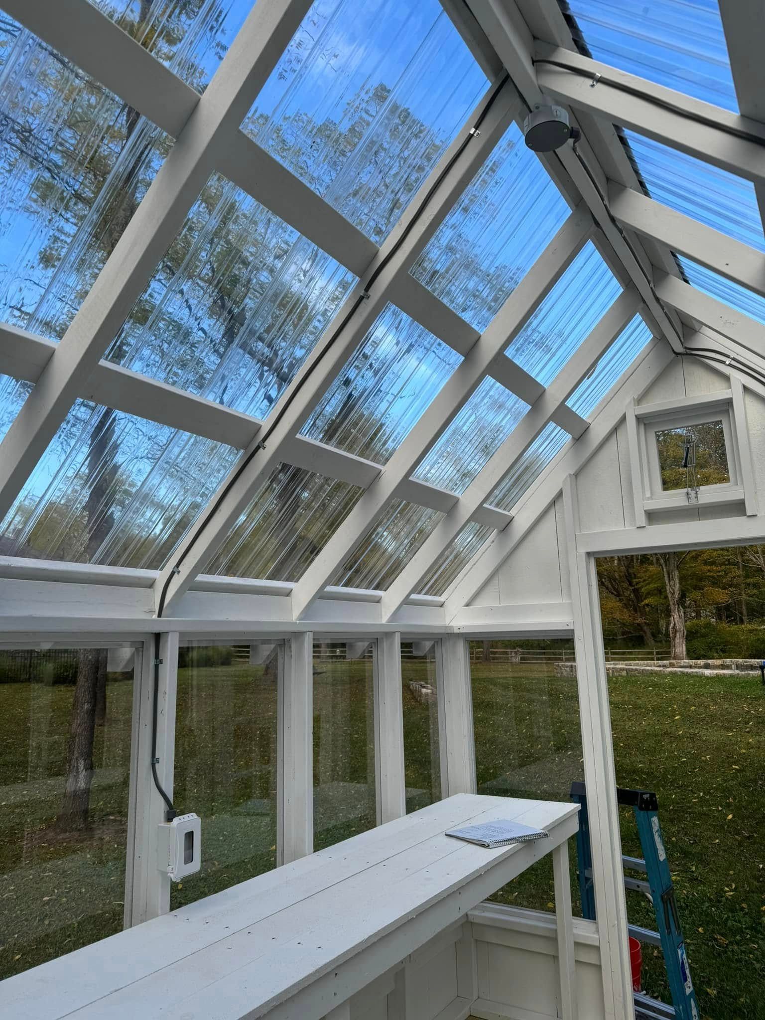 A greenhouse with a lot of windows and a ladder in the background.