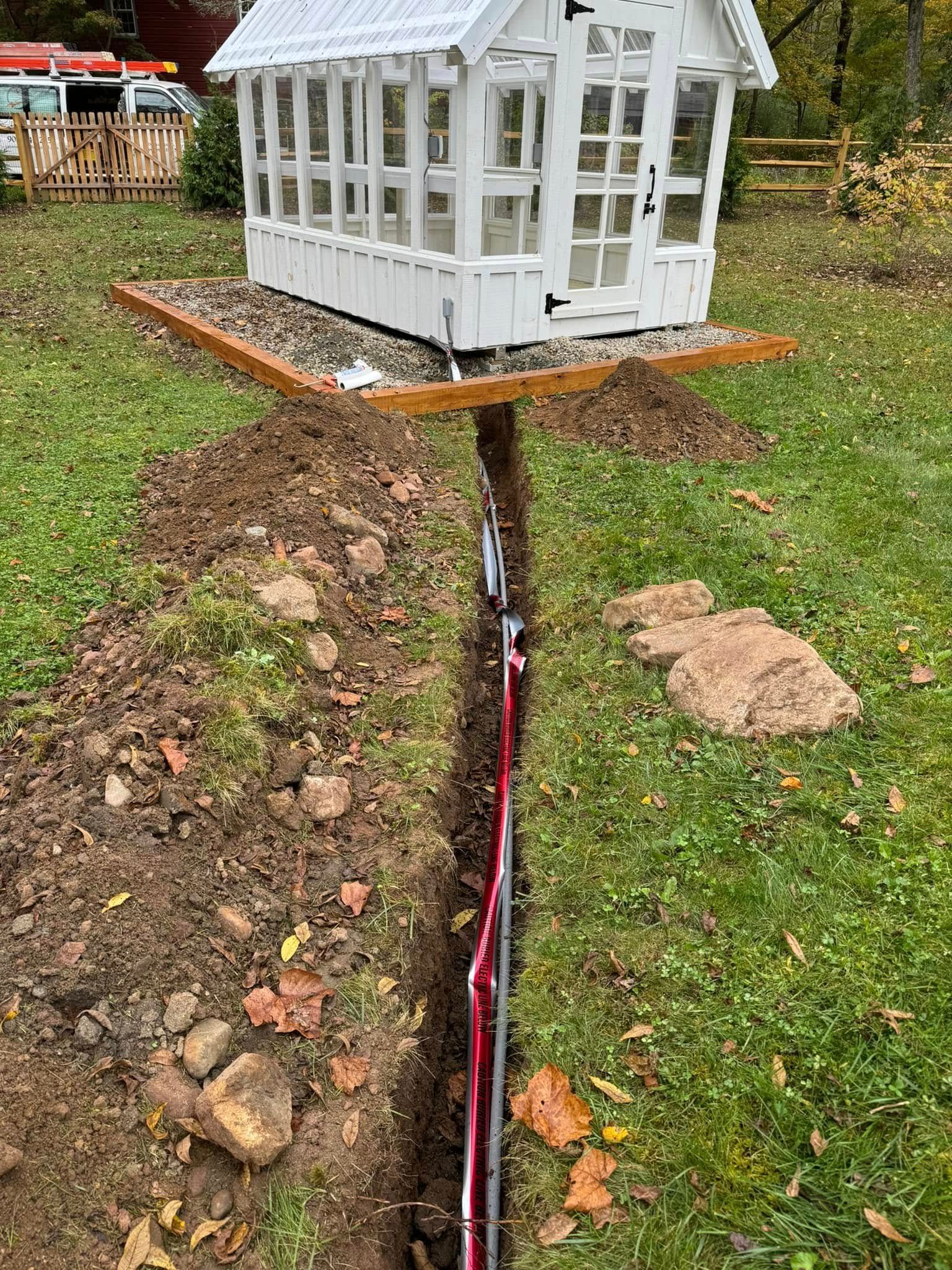 A small white greenhouse is sitting on top of a dirt hill.