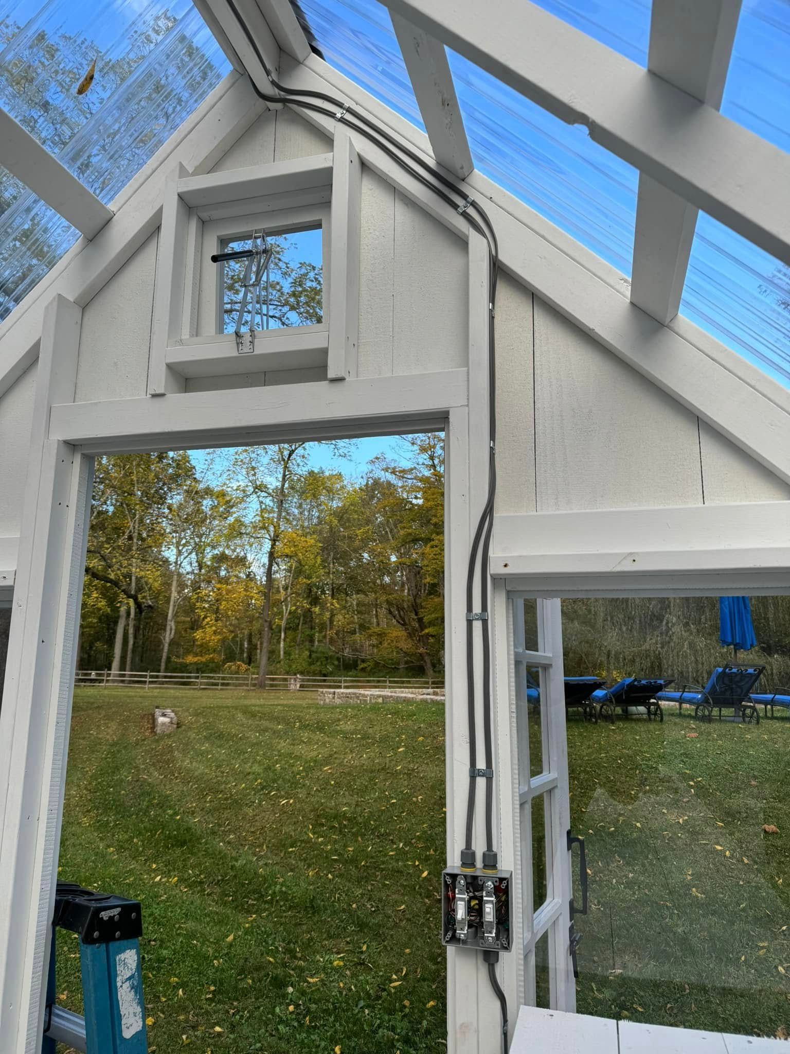 The inside of a greenhouse with a window and a ladder.