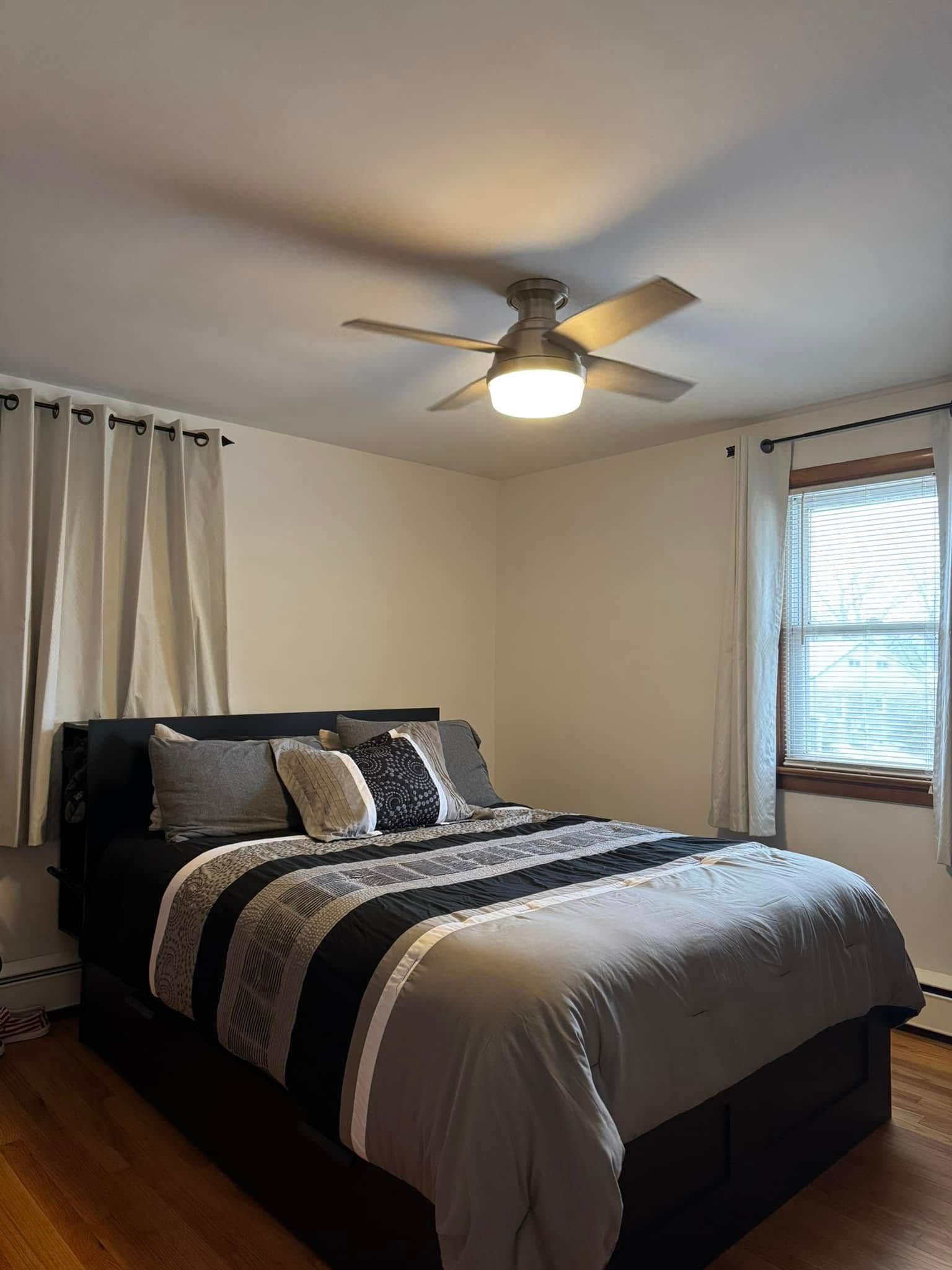 A bedroom with a bed and a ceiling fan.