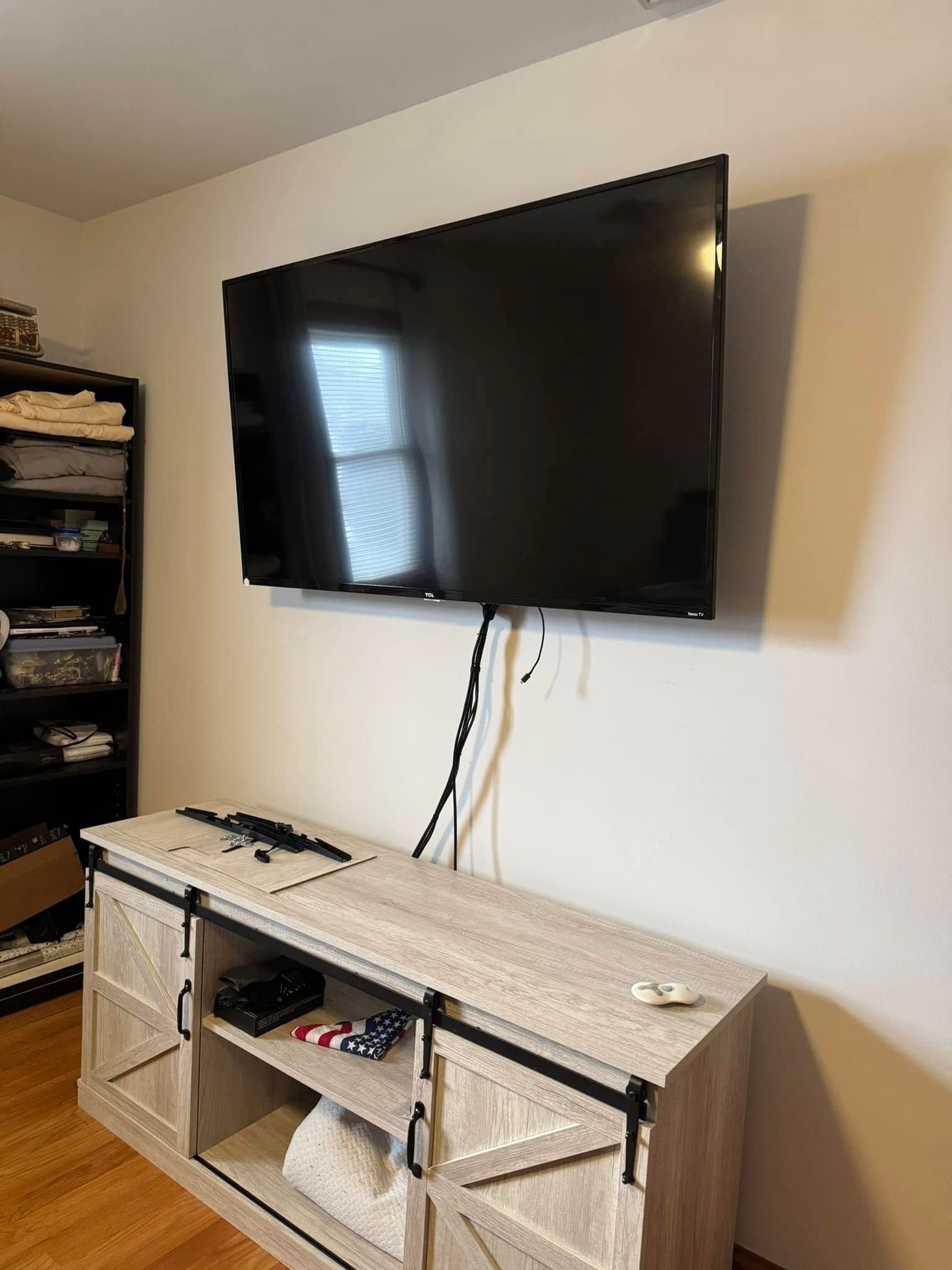 A flat screen tv is mounted to the wall above a sliding barn door entertainment center.