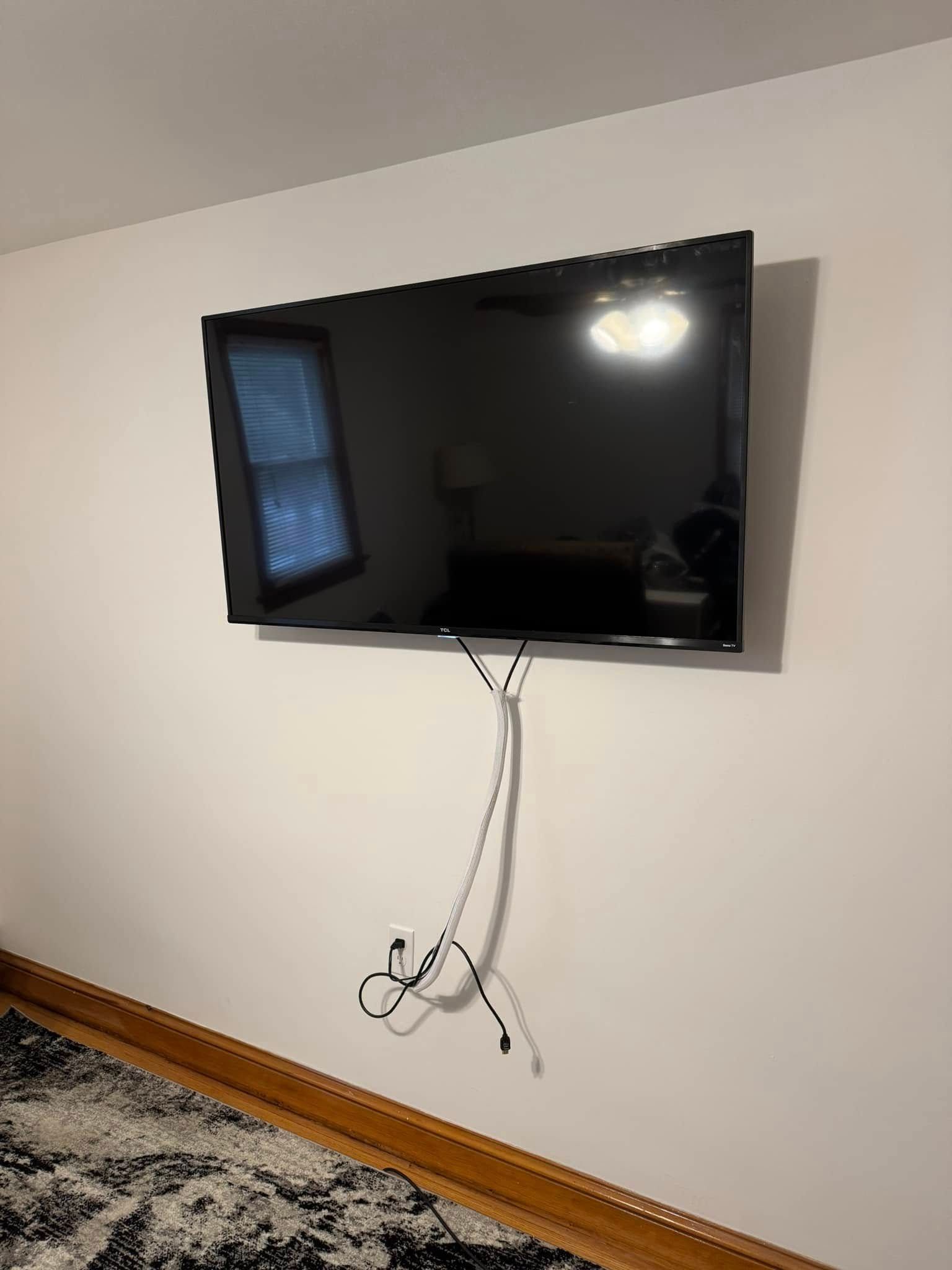 A flat screen tv is hanging on a white wall in a living room.