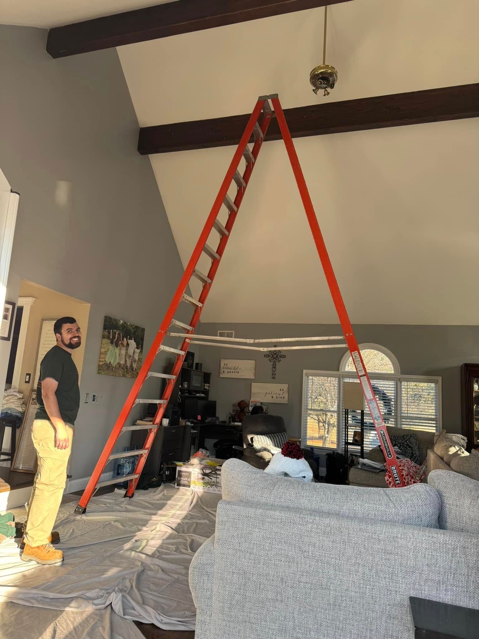 A man is standing next to a ladder in a living room.