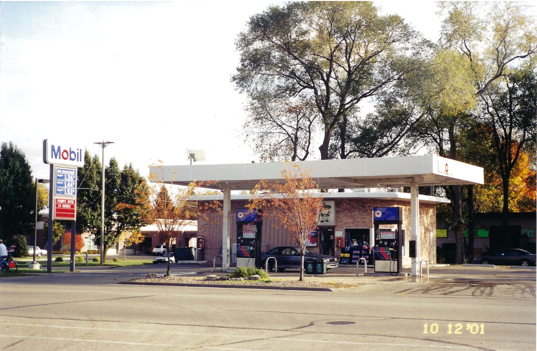 Mobil gas station with pumps under canopy, trees in background.