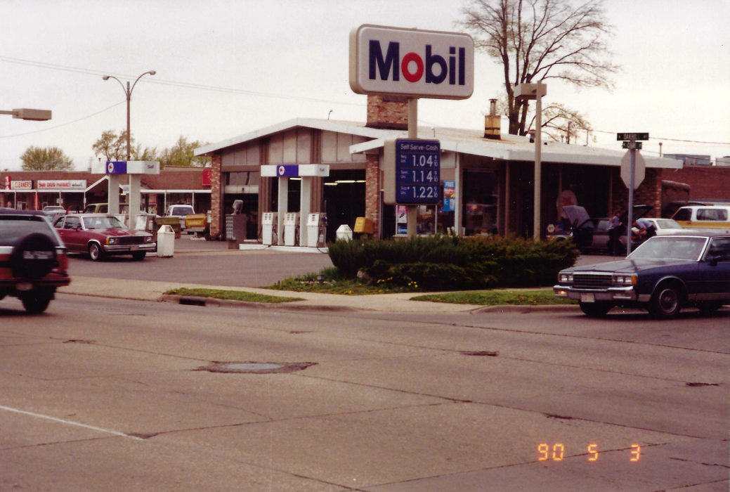 Mobil gas station with price sign; cars on street, overcast day.