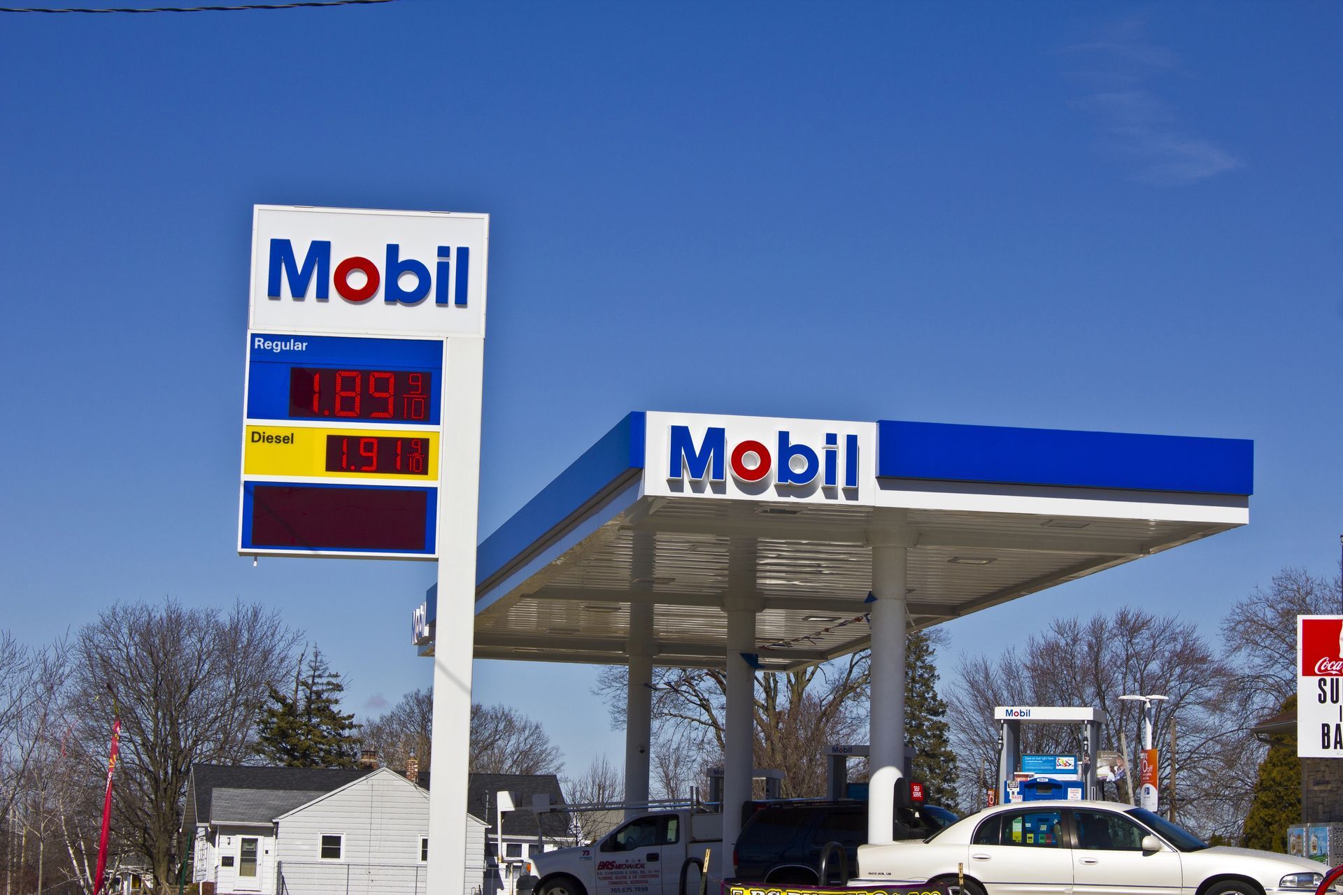 Mobil gas station with a blue and white canopy under a clear sky.  Gas price sign shows $1.899 for regular.