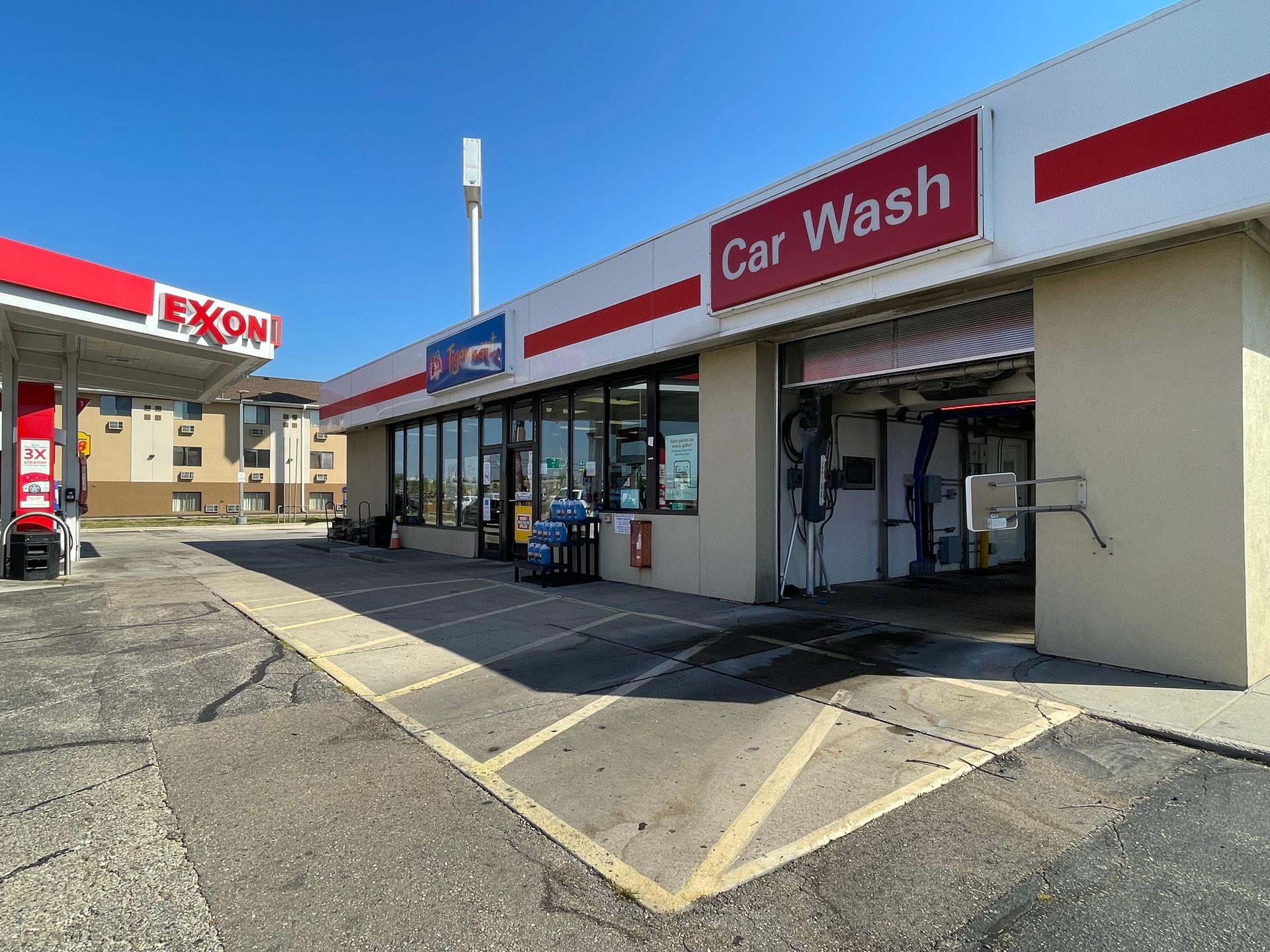Exxon gas station with convenience store and car wash on a sunny day.
