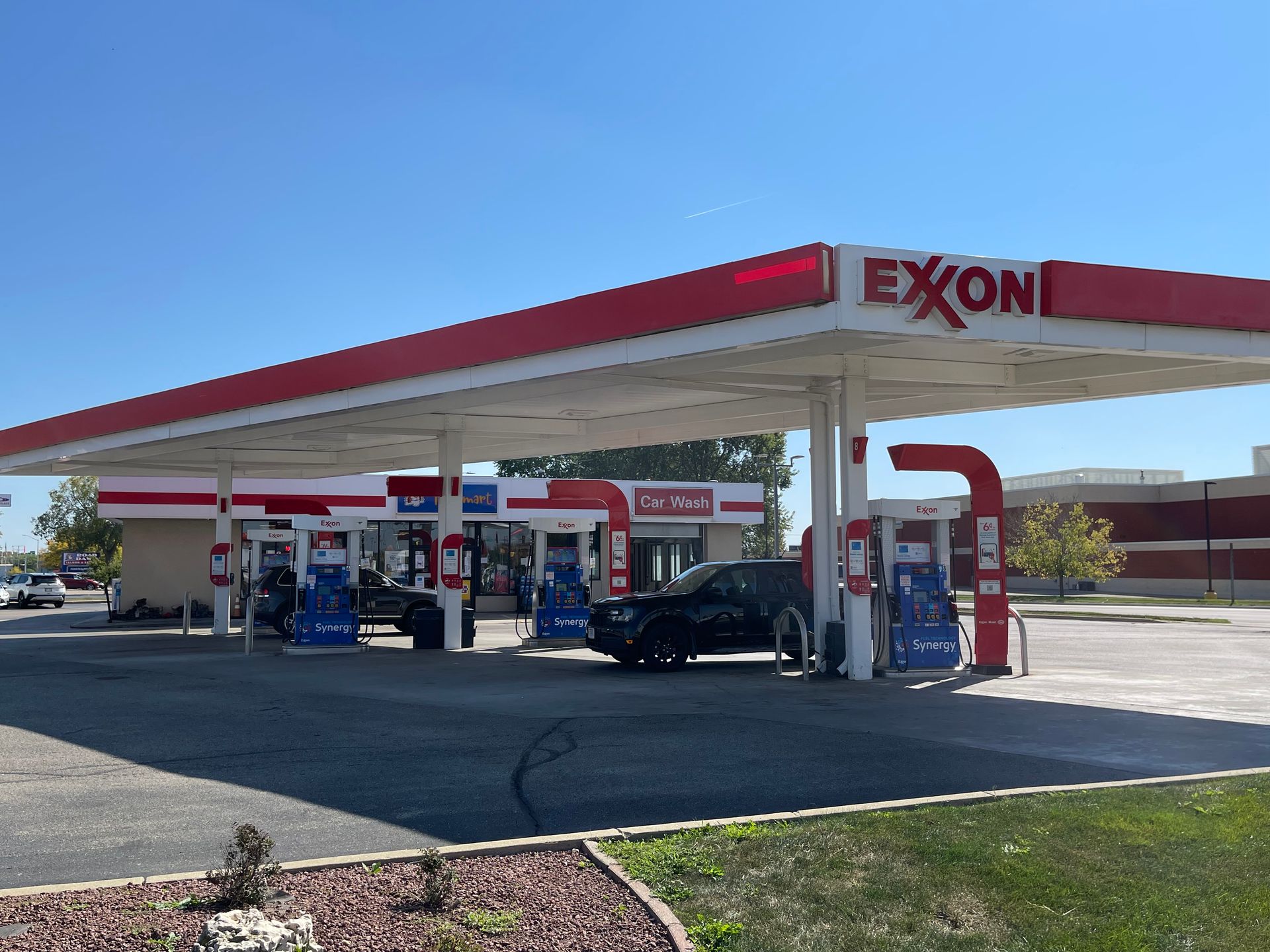 Exxon gas station with red and white canopy, pumps, and store on a sunny day.