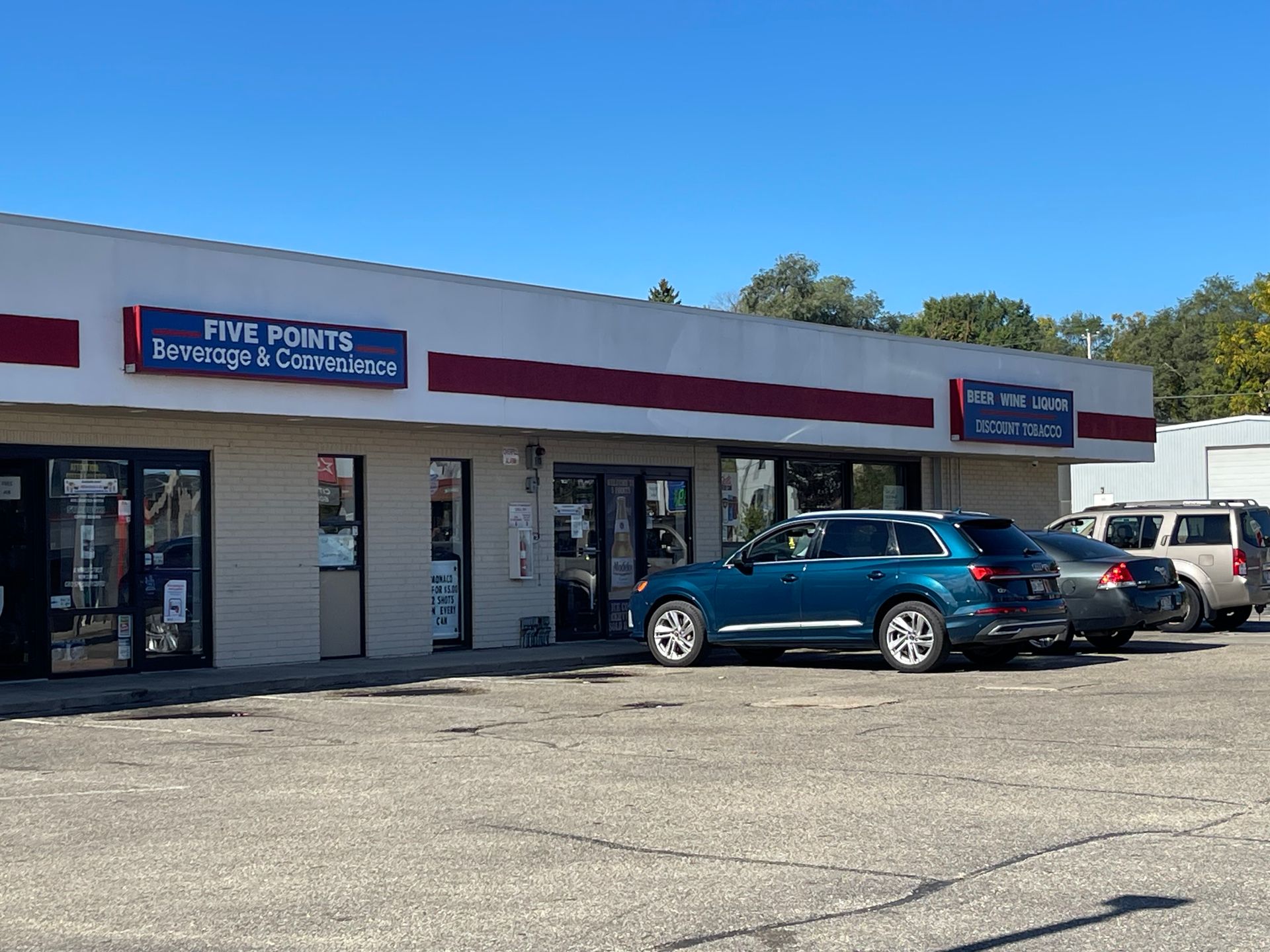Exterior of a store, "Five Points Beverages & Convenience," with a blue SUV parked out front.