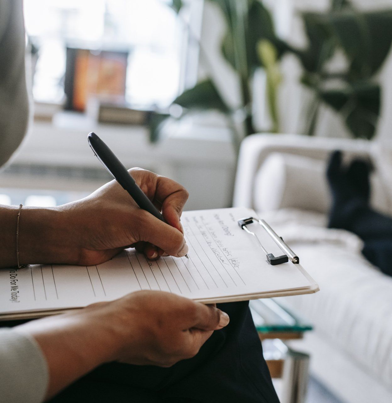 A person writing on a clipboard, likely in a counseling session.