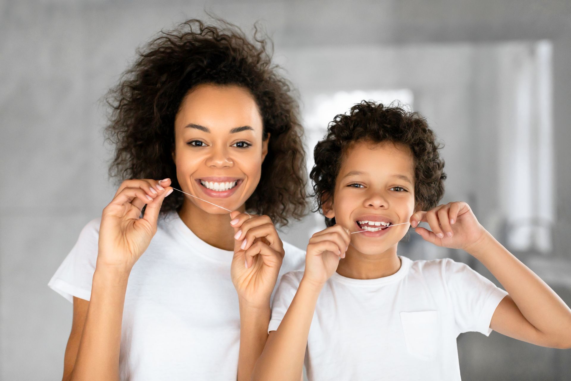 Adult and child flossing teeth together, promoting family dental hygiene habits. Adult and child flossing teeth together, promoting family dental hygiene habits.