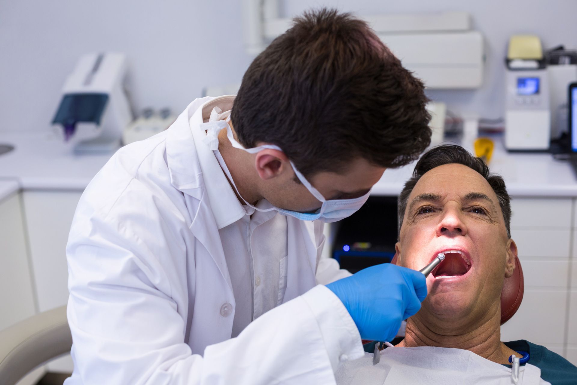 Dentist examining a male patient with tools in the clinic. Dentist examining a male patient with tools in the clinic.