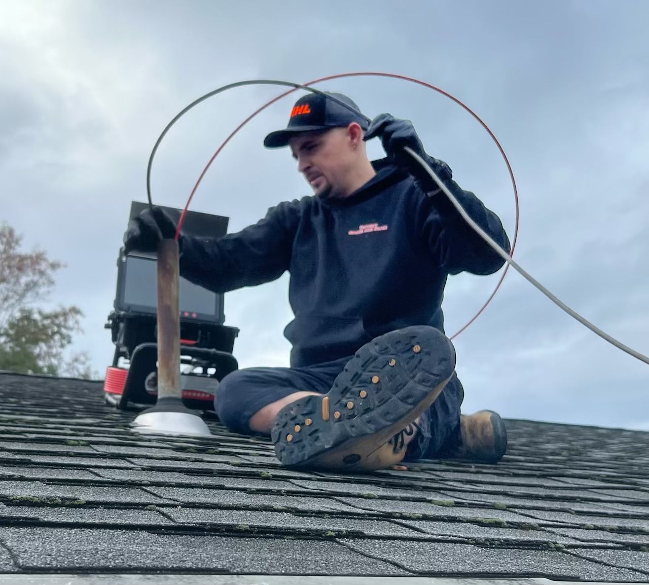 A man is sitting on a roof using a camera