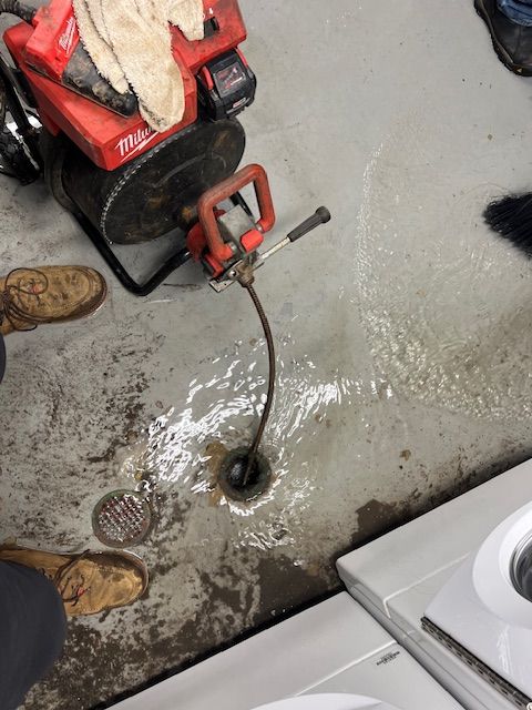 A person is using a snake to remove a drain