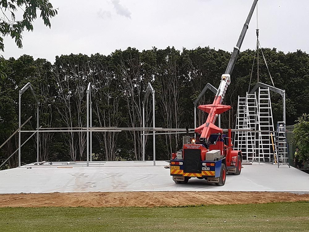Building Steel Shed With Orange Crane Equipment — CJR Group Concrete Construction In Lismore, NSW