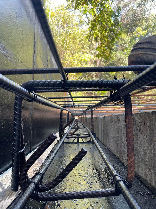 A Close-up Of A Rebar Structure With Trees In The Background — CJR Group Concrete Construction In Byron Bay, NSW