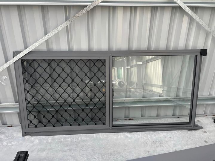 A Window With a Chain Link Fence on It is Sitting on the Ground — Providing Steel & Concrete Construction In Eviron, NSW