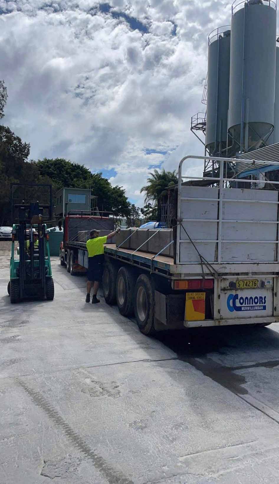 Man Is Pushing A Truck With A Forklift In The Background — Providing Steel & Concrete Construction In Lismore, NSW