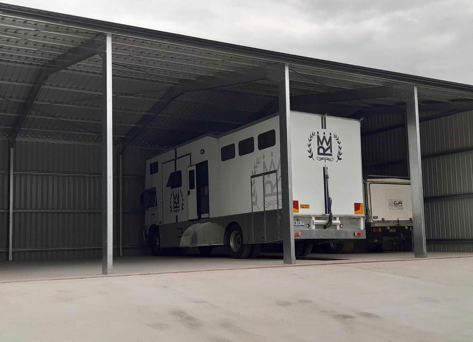 White Truck Is Parked Under A Metal Structure — Providing Steel & Concrete Construction In Lismore, NSW